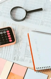 Magnifying glass and calculator on financial documents symbolizing data analysis and auditing
